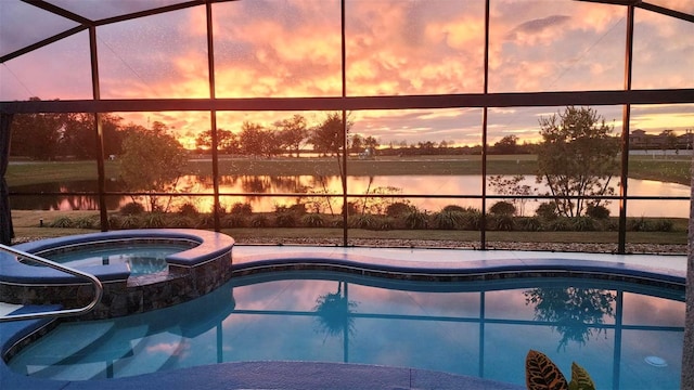 pool at dusk with an in ground hot tub and a water view