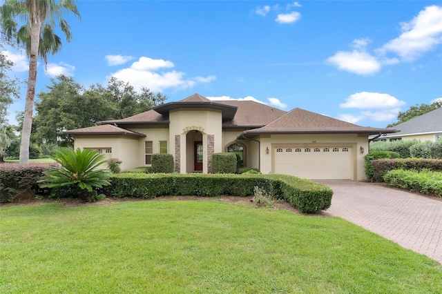 view of front of home featuring an attached garage, a front lawn, decorative driveway, and stucco siding