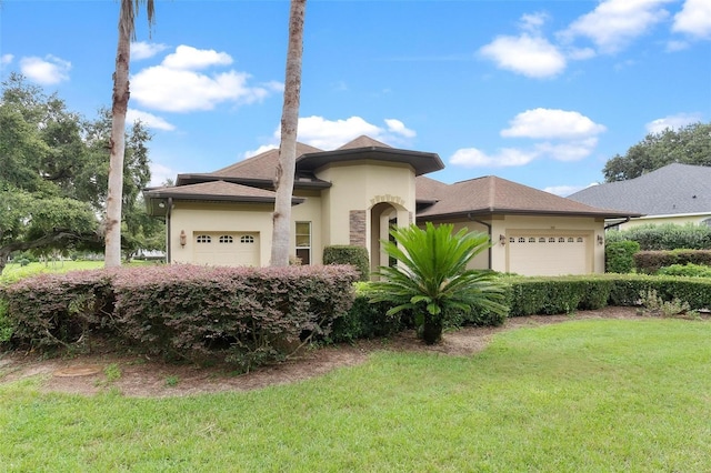 view of front of home with an attached garage, a front lawn, and stucco siding