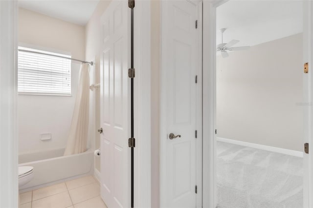 bathroom with ceiling fan, toilet, shower / bath combo with shower curtain, and tile patterned floors