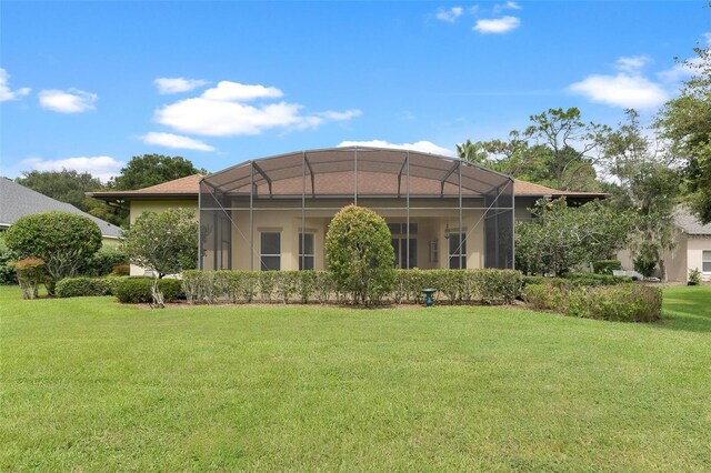 rear view of property with a lanai and a yard