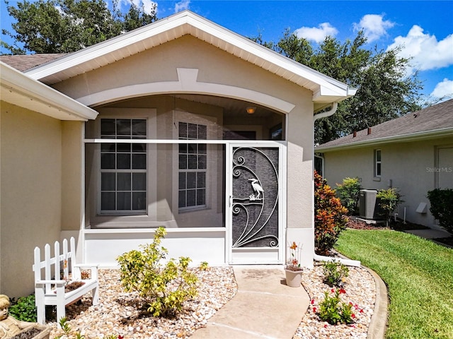 property entrance featuring fence, central AC, and stucco siding