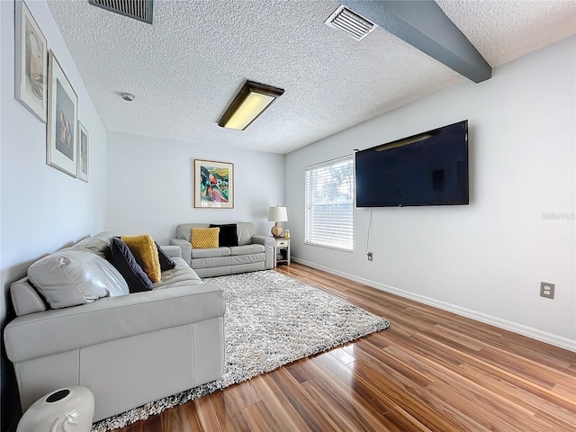 living room with hardwood / wood-style floors, beam ceiling, and a textured ceiling