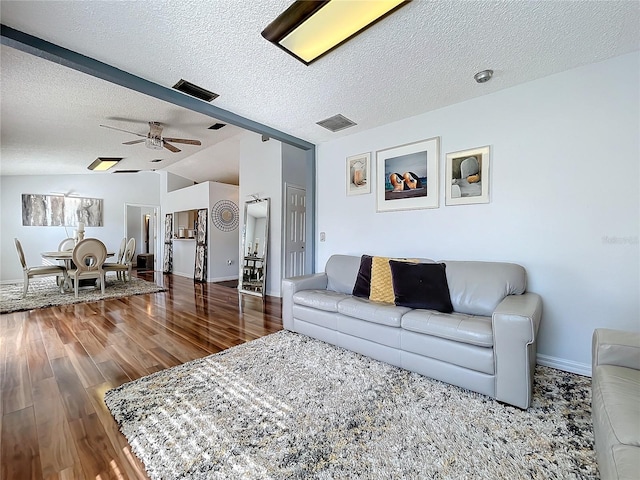 living room featuring lofted ceiling, a textured ceiling, wood-type flooring, and ceiling fan