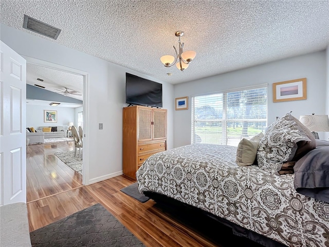 bedroom featuring a textured ceiling, a notable chandelier, and hardwood / wood-style flooring