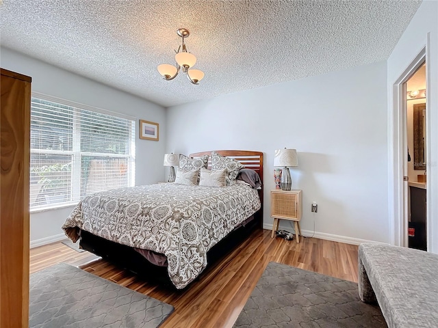 bedroom featuring a textured ceiling, hardwood / wood-style flooring, and an inviting chandelier