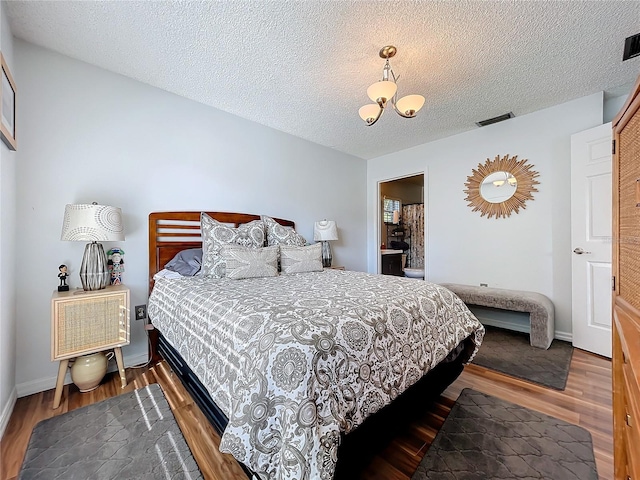 bedroom featuring a notable chandelier, wood-type flooring, and a textured ceiling