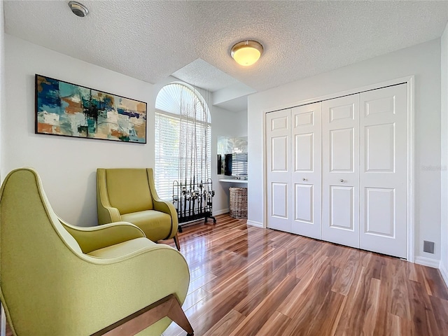 sitting room with wood-type flooring and a textured ceiling