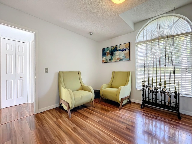 sitting room with hardwood / wood-style floors and a textured ceiling