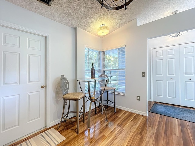 entrance foyer with lofted ceiling, a textured ceiling, and wood-type flooring