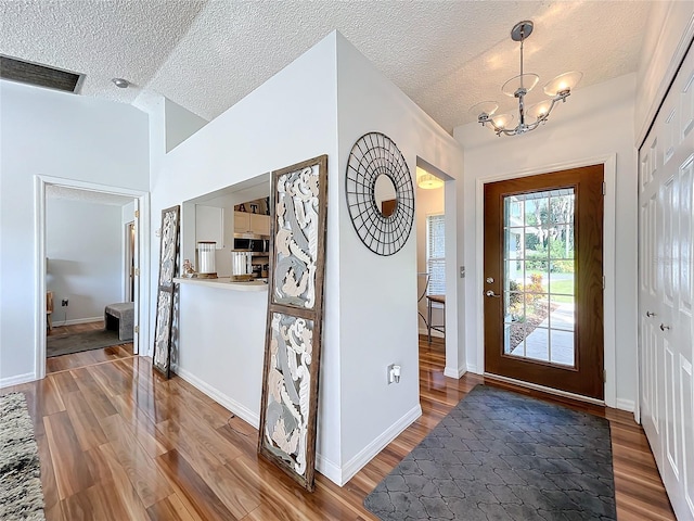 foyer entrance with hardwood / wood-style floors, a textured ceiling, and vaulted ceiling