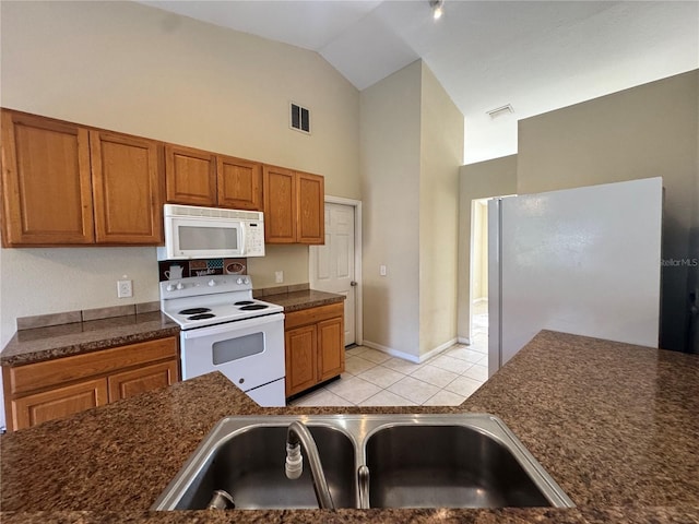 kitchen featuring light tile patterned flooring, white appliances, sink, and high vaulted ceiling