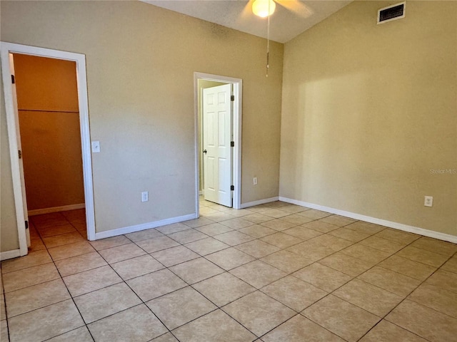 empty room with ceiling fan, light tile patterned floors, and lofted ceiling