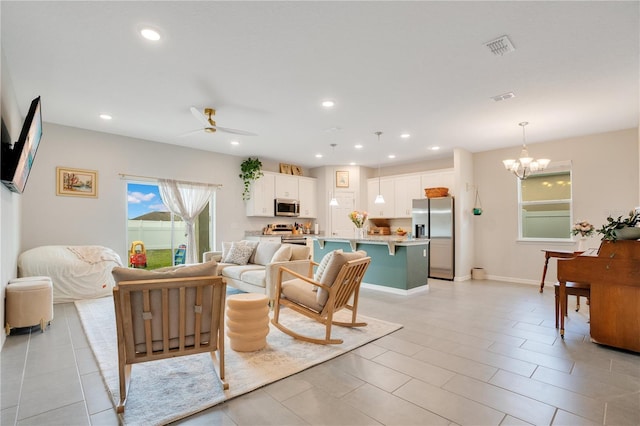 living room with ceiling fan with notable chandelier and light tile patterned floors