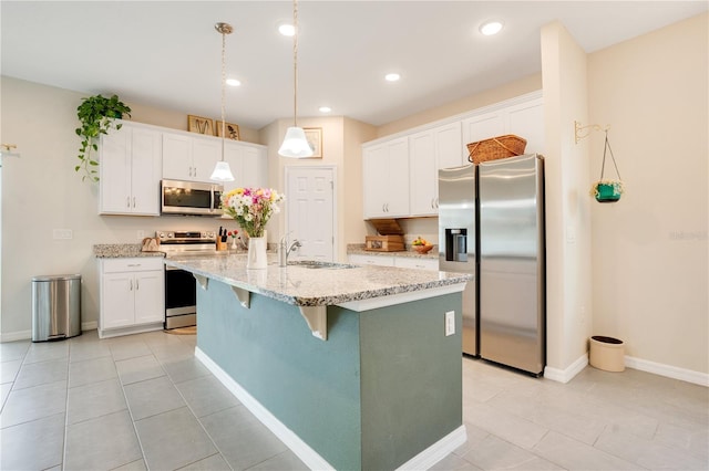 kitchen with light tile patterned floors, appliances with stainless steel finishes, white cabinets, and a kitchen island with sink