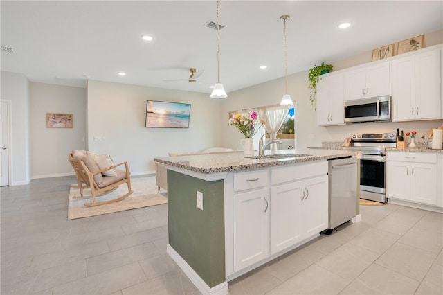 kitchen featuring appliances with stainless steel finishes, light tile patterned floors, an island with sink, and white cabinets