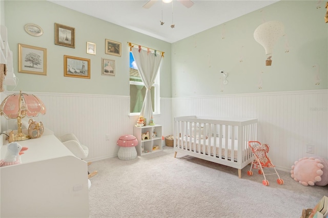 bedroom with a nursery area, carpet, and ceiling fan