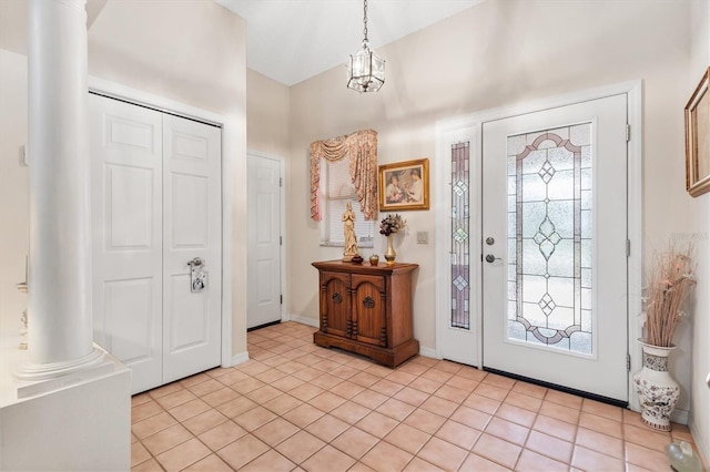 entryway with decorative columns, light tile patterned floors, and a notable chandelier