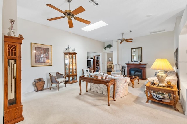 carpeted living area featuring ceiling fan, a skylight, a glass covered fireplace, and visible vents