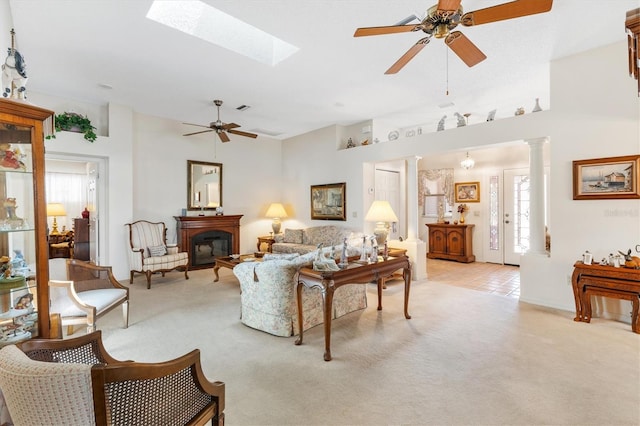 carpeted living room featuring decorative columns, a skylight, and ceiling fan