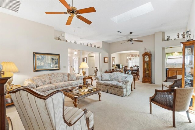 carpeted living room featuring a skylight and ceiling fan with notable chandelier