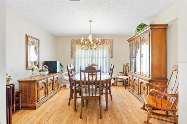 dining area featuring a textured ceiling, light wood-type flooring, and a chandelier