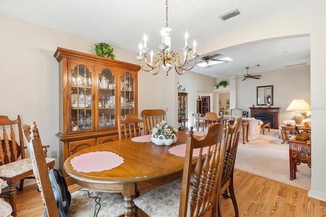 dining room featuring a textured ceiling, light hardwood / wood-style flooring, and ceiling fan with notable chandelier