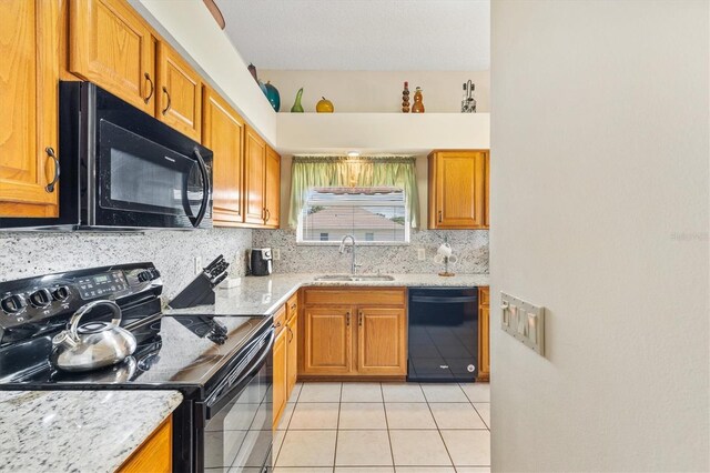 kitchen featuring light tile patterned floors, black appliances, light stone counters, sink, and decorative backsplash