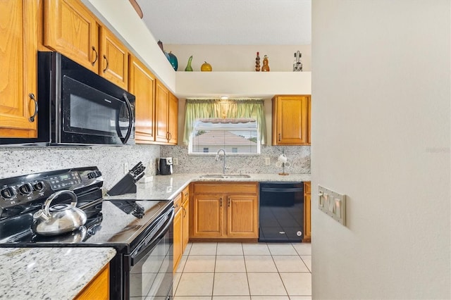 kitchen with tasteful backsplash, light tile patterned flooring, a sink, light stone countertops, and black appliances