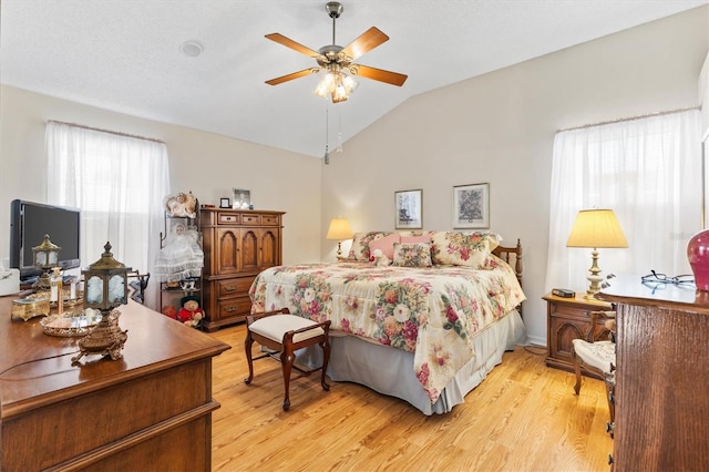 bedroom with lofted ceiling and light wood-style floors