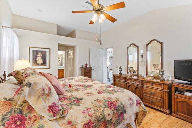 bedroom with light wood-type flooring, ceiling fan, ensuite bath, and vaulted ceiling