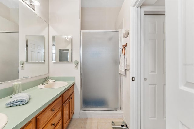 bathroom featuring double vanity, tile patterned flooring, a shower stall, and a sink