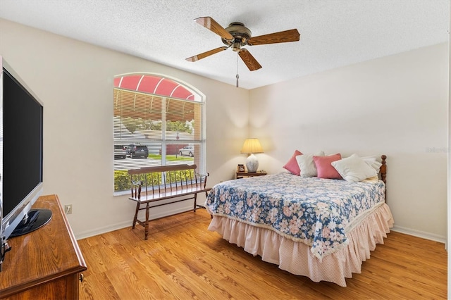 bedroom with a textured ceiling, ceiling fan, and light wood-type flooring