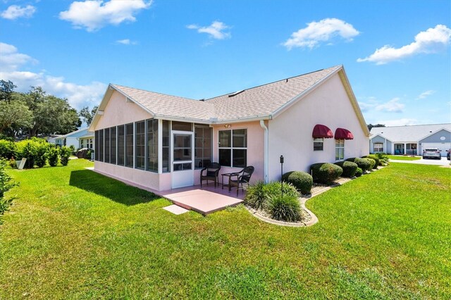 rear view of property with a lawn, a patio, and a sunroom