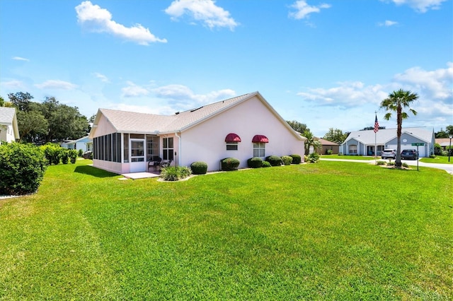 view of side of property featuring a sunroom and a lawn