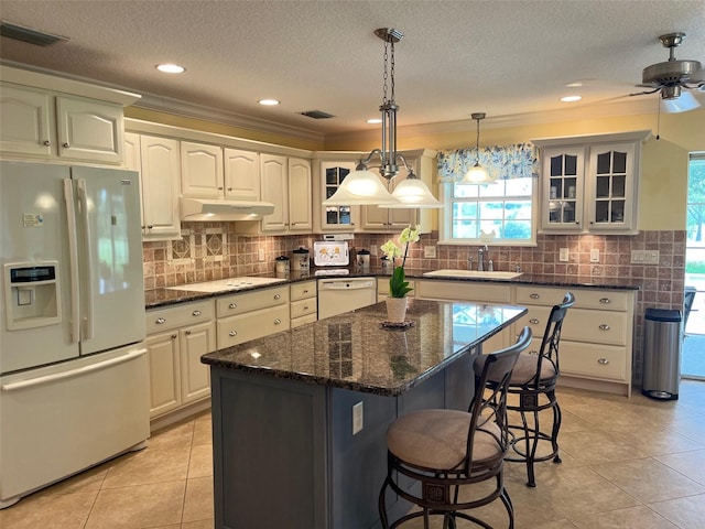 kitchen featuring white appliances, ceiling fan, sink, white cabinets, and a center island