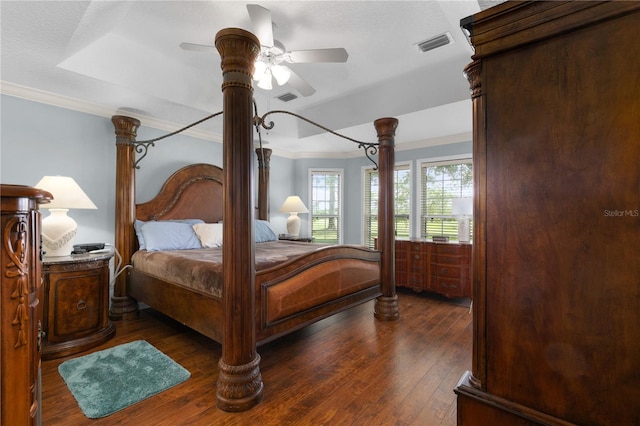 bedroom with ornamental molding, a tray ceiling, ceiling fan, and dark wood-type flooring