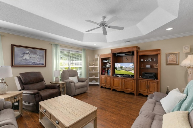 living room with a textured ceiling, a tray ceiling, ceiling fan, dark wood-type flooring, and crown molding