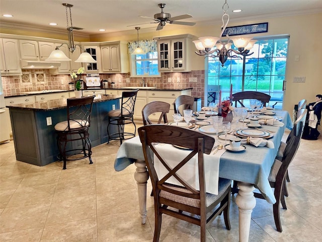 tiled dining area with ceiling fan with notable chandelier and ornamental molding