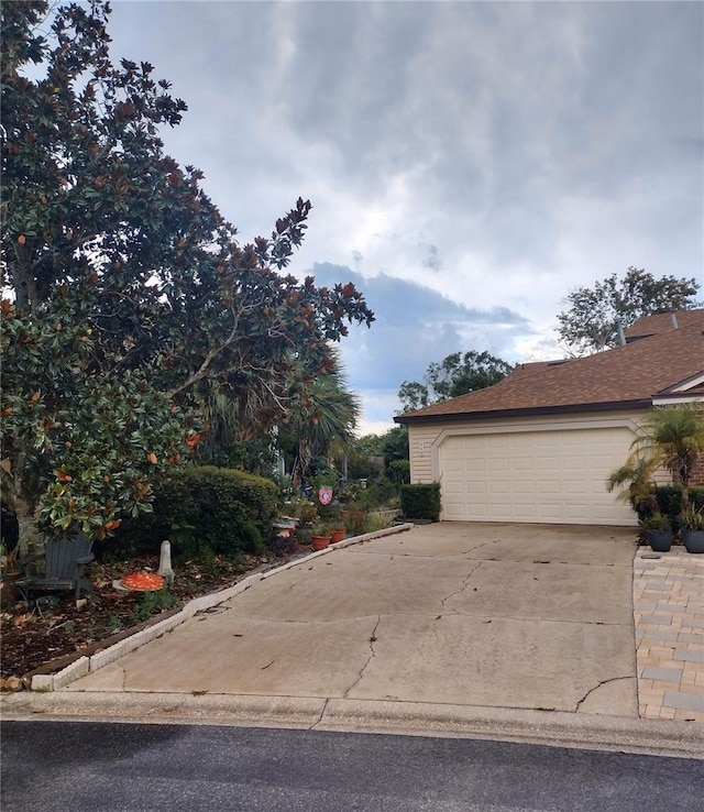 exterior space with a garage, driveway, and roof with shingles