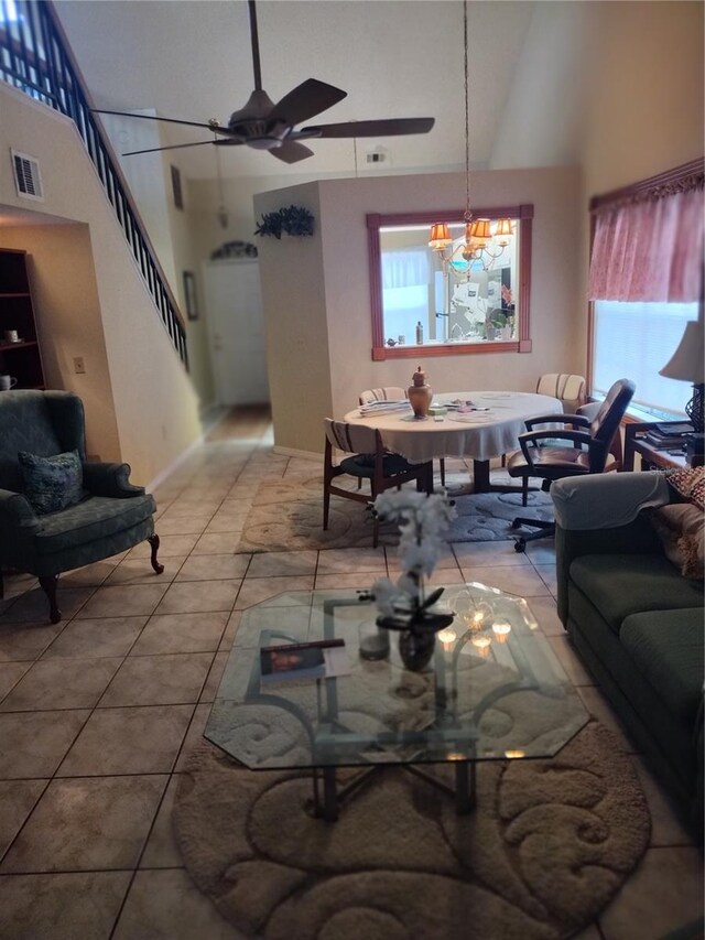 tiled living room featuring ceiling fan with notable chandelier and vaulted ceiling