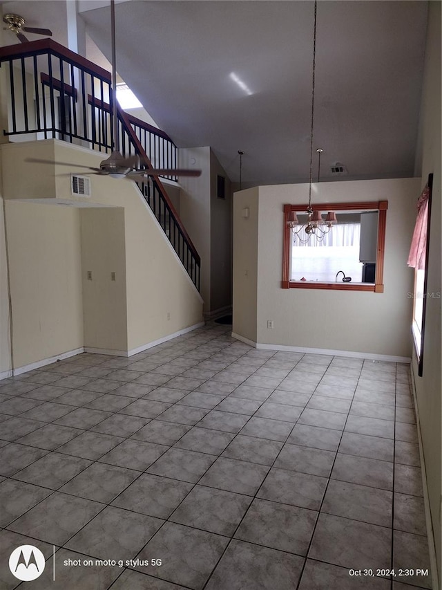 unfurnished living room featuring high vaulted ceiling, tile patterned floors, and a notable chandelier