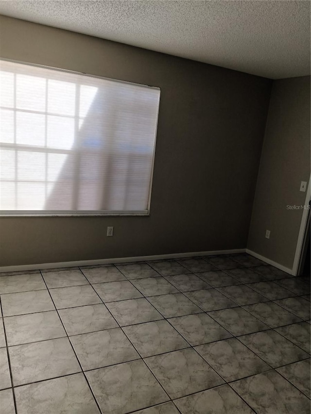 spare room with tile patterned floors and a textured ceiling