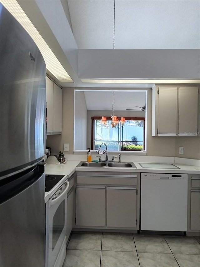 kitchen featuring sink, decorative light fixtures, light tile patterned floors, white appliances, and lofted ceiling