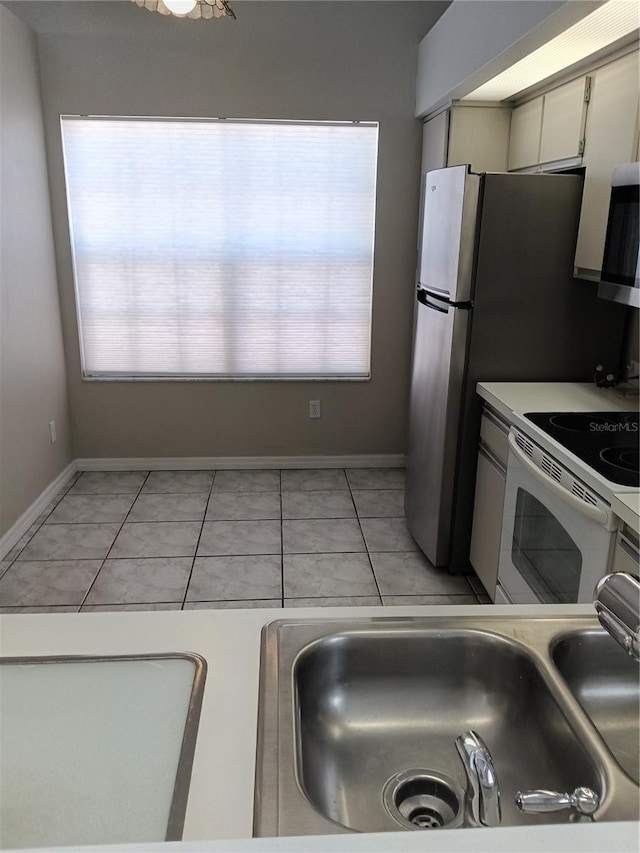 kitchen with sink, white cabinets, light tile patterned floors, and white electric range