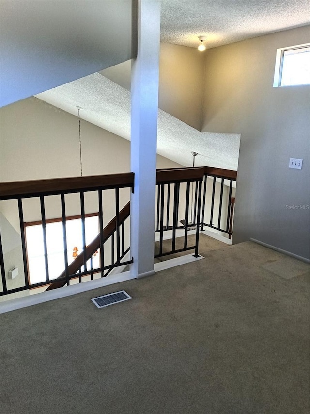 interior space with vaulted ceiling, a textured ceiling, and carpet floors