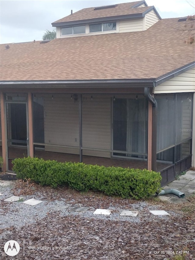 back of property featuring a sunroom and roof with shingles