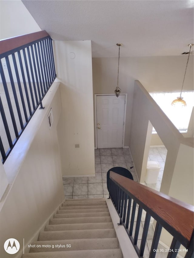 stairway featuring baseboards, visible vents, and tile patterned floors