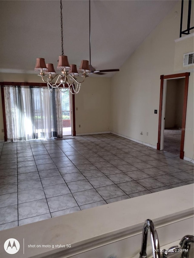 empty room with light tile patterned floors, ceiling fan with notable chandelier, visible vents, baseboards, and vaulted ceiling