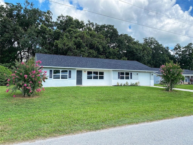 ranch-style home featuring a garage and a front lawn